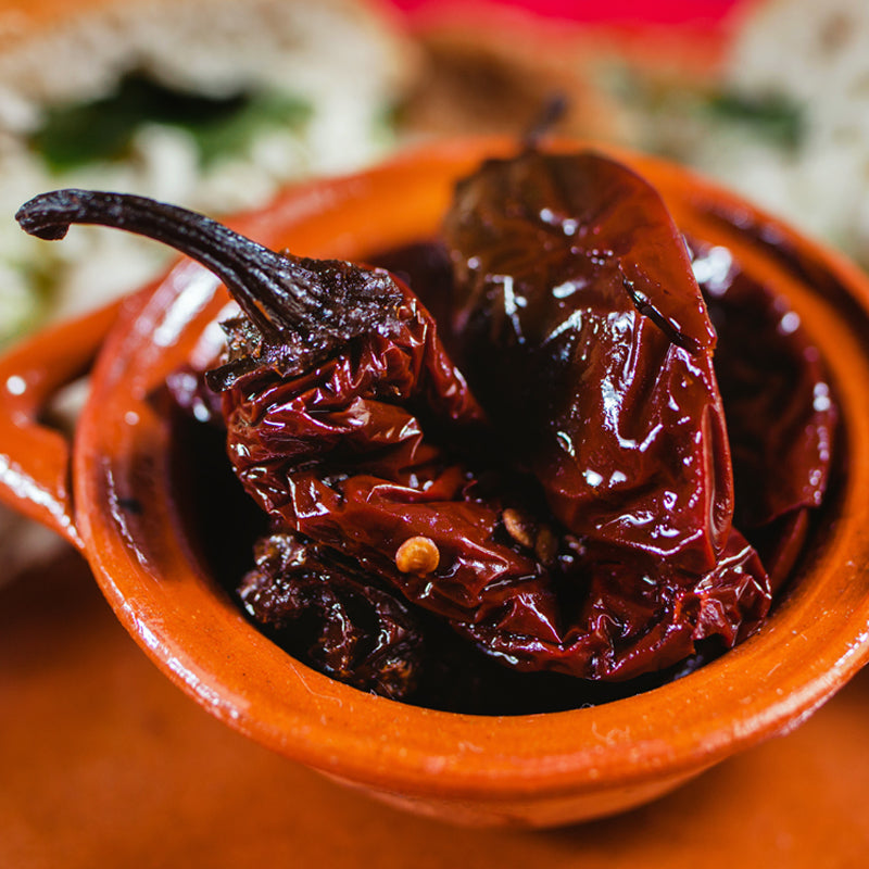 Dried red chilies in a terracotta bowl on a wooden surface