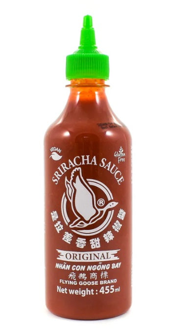 Bottle of Sriracha sauce with a green cap on a white background